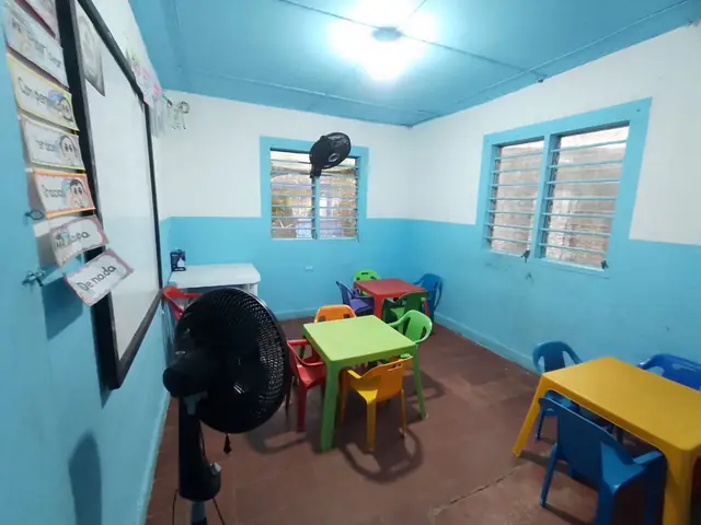 Aula de preescolar con mesas y sillas pequeñas de colores.