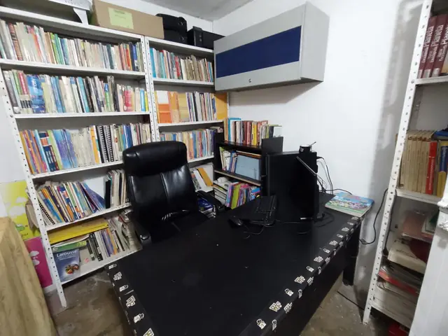 Estantes llenos de libros y un escritorio con computador.