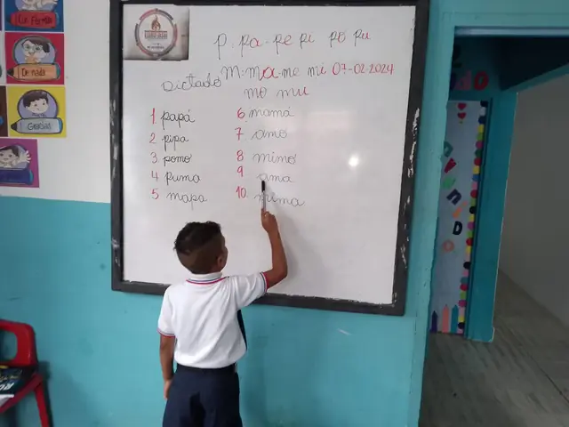 Un niño de uniforme, de espaldas, señala palabras de un dictado en el tablero.